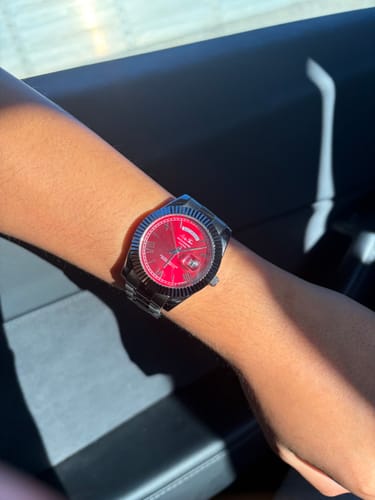 Customer wearing their Lucky Fours® Santos watch with a red dial on their wrist in a car.