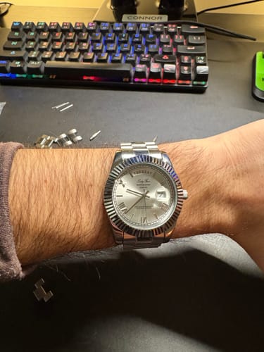Customer wearing the silver Lucky Fours® Santos watch on their wrist, with removed band links on the desk.