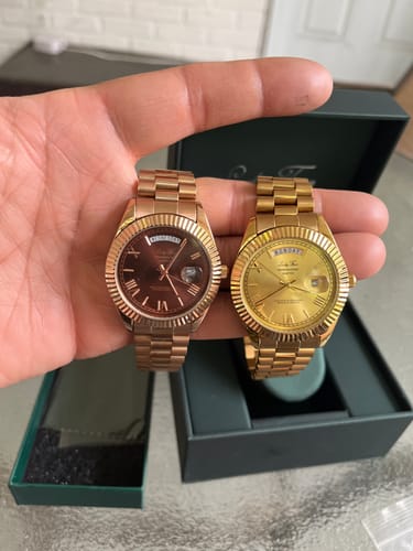 Customer's hand holding a rose gold and a gold Lucky Fours® Santos watch for comparison.