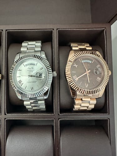 Customer's silver and rose gold Lucky Fours® Santos watches displayed side-by-side in a dark watch box.