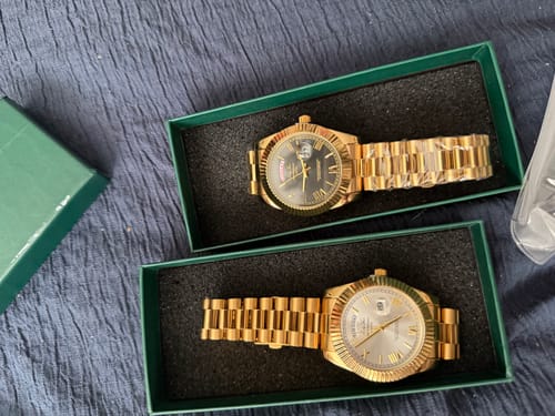 Customer's two gold-colored Lucky Fours® Santos watches with different faces displayed in green presentation boxes.