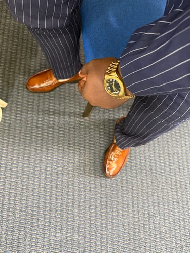 Customer wearing shiny brown Lucky Fours® Santos loafers with a navy pinstripe suit, seen from above.