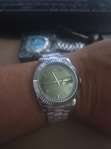 Customer wearing the silver-colored watch with a green dial on their wrist.