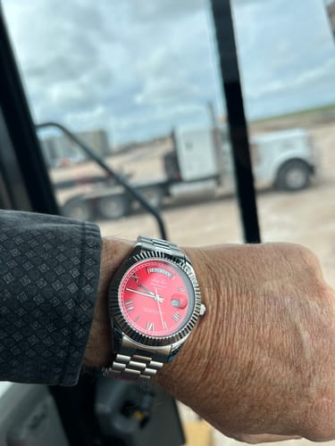 Customer wearing the Lucky Fours® Santos watch with a red dial and silver band on their wrist at a work site.